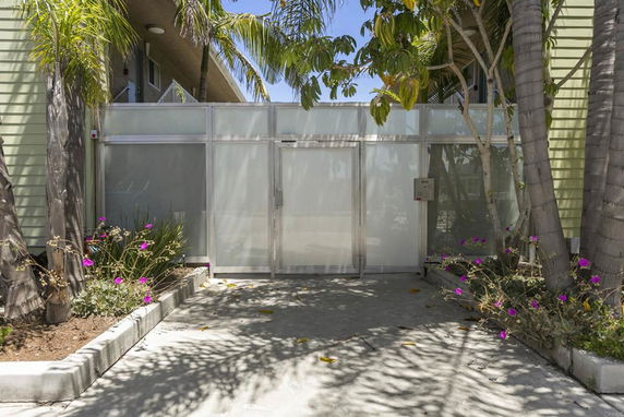 Front view of a building with frosted glass entrance and surrounding plants.
