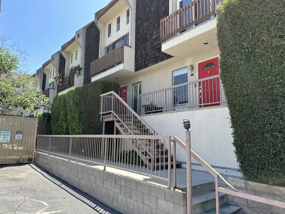 Front view of a multi-story building with balconies and a prominent red door.