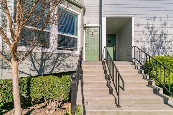 Front view of a two-story house with green front door and concrete steps leading up to the entrance.