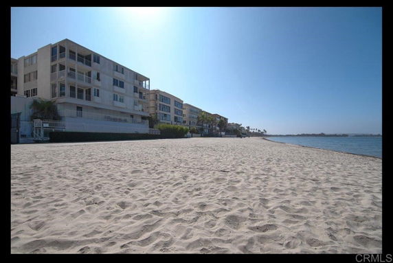 Beachfront view of multi-story residential buildings along a sandy shoreline.