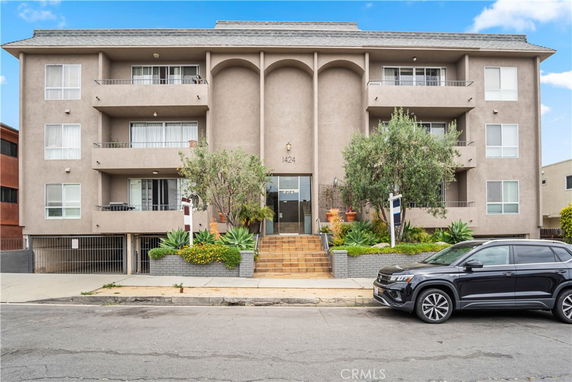 Front view of a multi-story building with balconies and a staircase leading to the entrance.