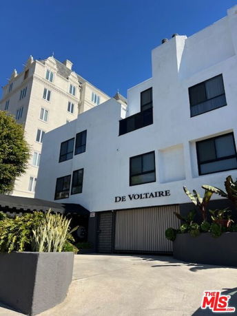 Front view of a multi-story building with the name De Voltaire on the facade.