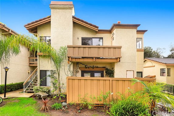 Front view of a two-story house with a balcony and fenced yard.