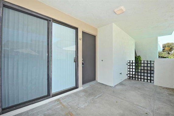Front view of a building entrance with a sliding glass door and an adjacent door.
