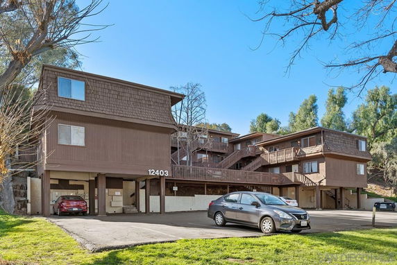 Front view of a multi-story apartment building with parking spaces underneath.