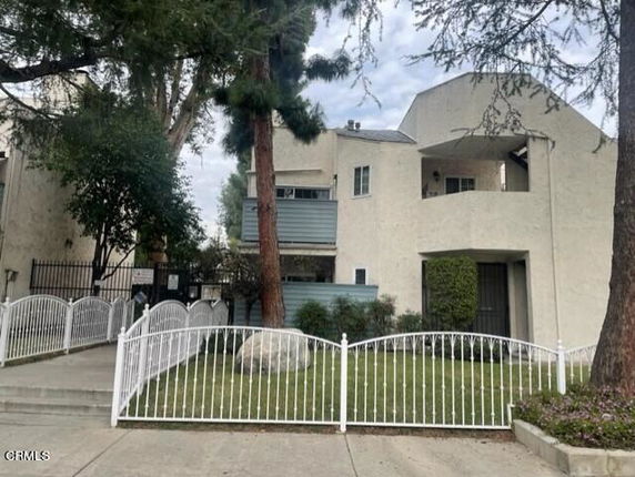 Front view of a multi-story residential building with balconies and a gated entrance.