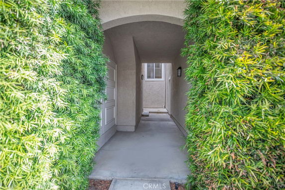 Entrance archway leading to a residential building with greenery on either side.