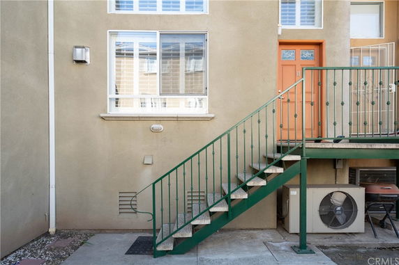 Exterior view of a building showing a staircase leading to an upper level entrance with a window beside it.