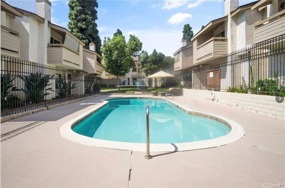 Outdoor swimming pool area surrounded by multi-story buildings with balconies.