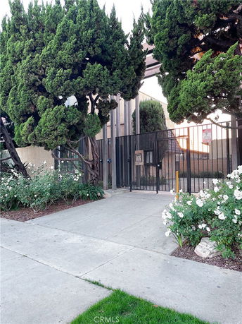 View of building entrance with surrounding trees and flowers.