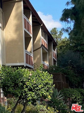 Angled view of a multi-story building with balconies and a sloped roof.