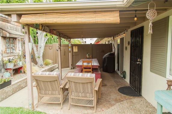 Outdoor covered patio area with chairs, a long table, and decorations.