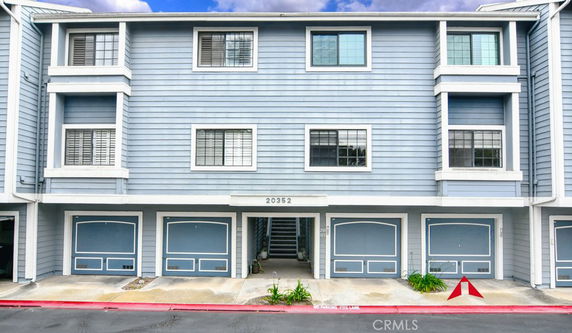 Front view of a multi-story house with blue siding and multiple garages.