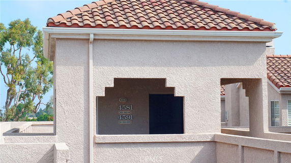 Front view of a building with a tile roof and decorative stucco elements.