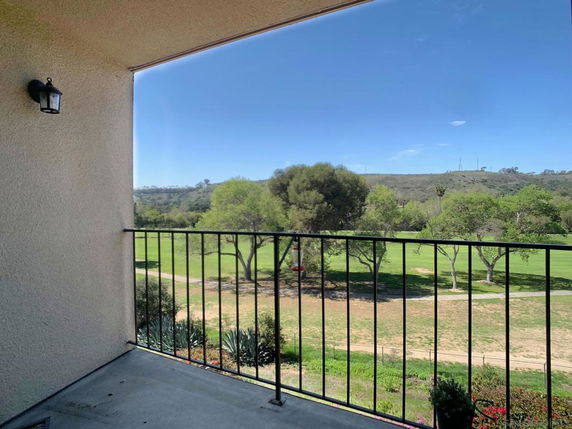 Panoramic view of a grassy landscape and hills from a balcony.