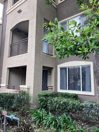 Front view of a multi-story building with balconies and a ground-level window.