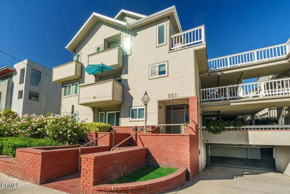 Front view of a multi-story house with balconies and garage.