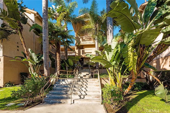 Front view of a residential building with multiple stories and tropical landscaping.