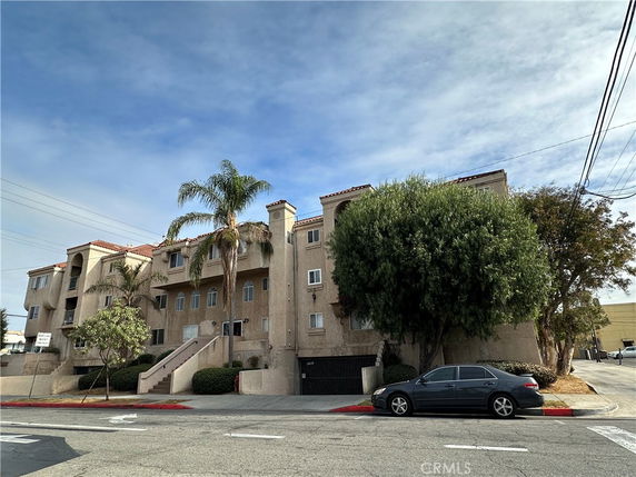 Front view of a multi-story apartment building with balconies and a staircase.