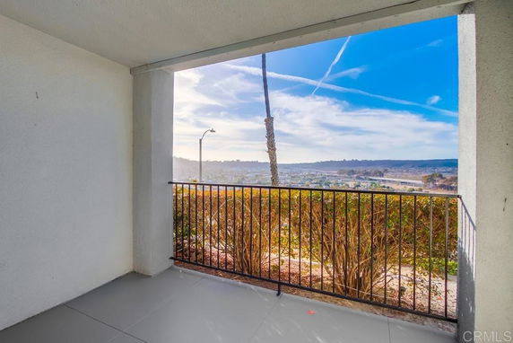 View from a covered outdoor balcony with railing overlooking a scenic landscape.