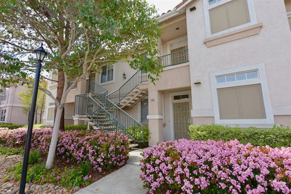 Front view of a two-story residential building with stairs and a balcony.
