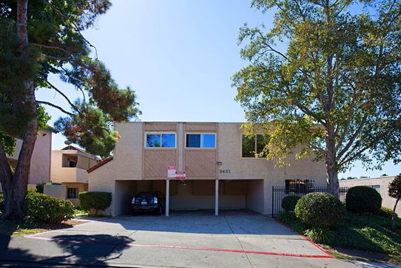 Front view of a two-story building with covered parking underneath.
