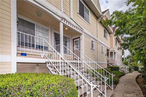 Front view of a multi-story townhouse with stairs leading to the entrance.