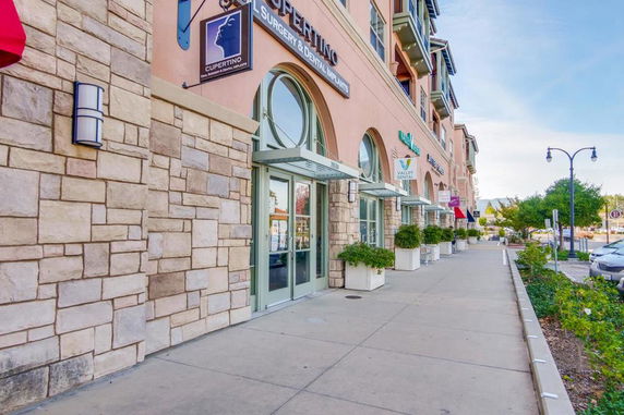 Side view of a commercial building with stone facade and storefronts.