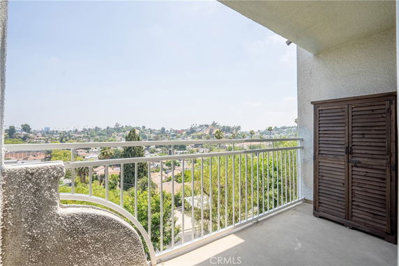 Balcony view overlooking a cityscape with greenery and buildings in the background.