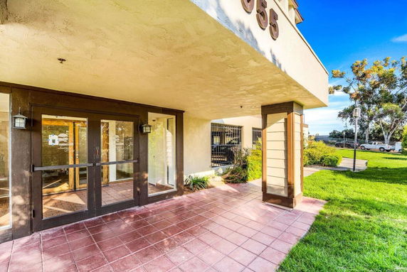 Front view of a building entrance with glass doors and tiled flooring.