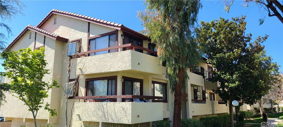 Front view of a multi-story apartment building with balconies and tiled roofs.