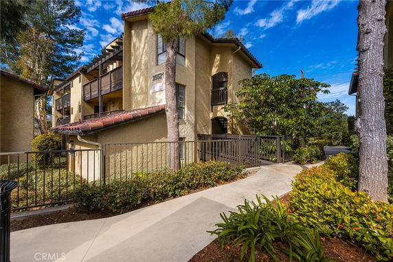 Front view of a multi-story residential building with balconies and a ramp entrance.