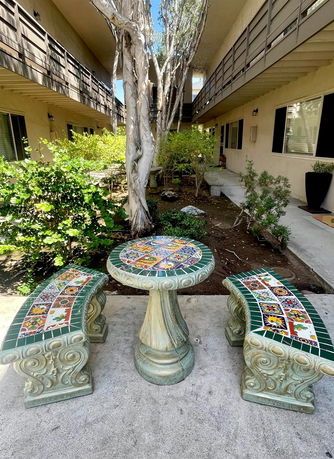 Outdoor area with decorative table and benches between two buildings.