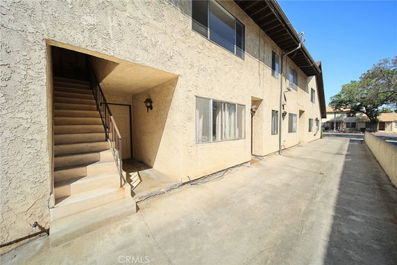 Front view of a two-story building with external staircase and windows.