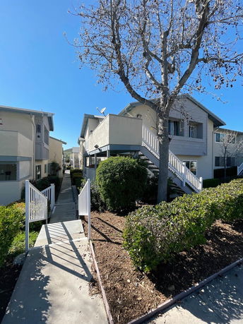 Front view of a multi-story apartment building with exterior stairs and railing.