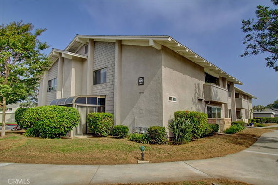 Front view of a two-story apartment building with a small entrance porch and multiple windows.