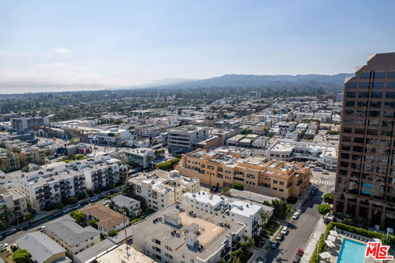 Panoramic view of a cityscape with multiple buildings and distant hills.