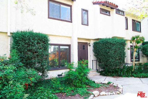 Front view of a multi-story building with shrubbery.