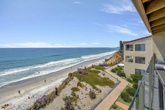 Panoramic view from a beachfront building overlooking the ocean and sandy beach.