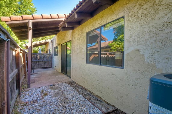 Side view of a single-story house with sliding windows and a covered patio.
