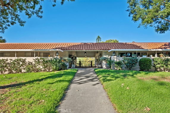 Front view of a single-story house with a red-tiled roof and a pathway leading to the entrance.