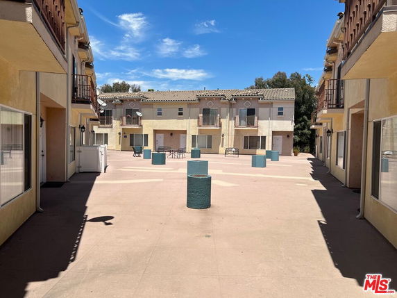 Front view of a two-story apartment complex with balconies and a central courtyard.