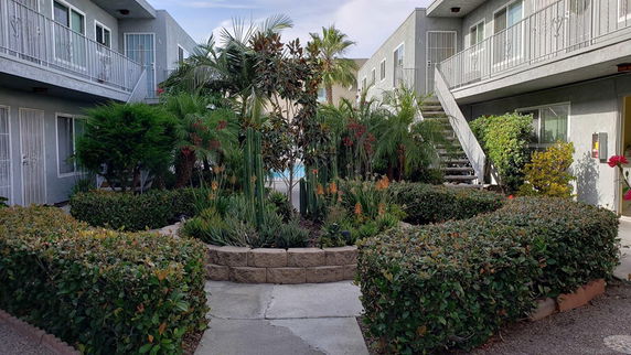 Outdoor view of an apartment complex with two-story buildings and a garden courtyard.
