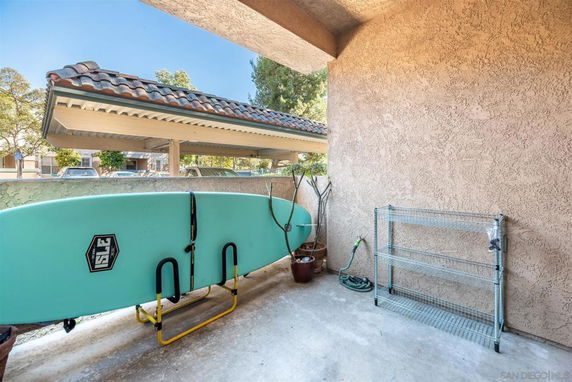 Covered parking area with a surfboard and metal shelving.