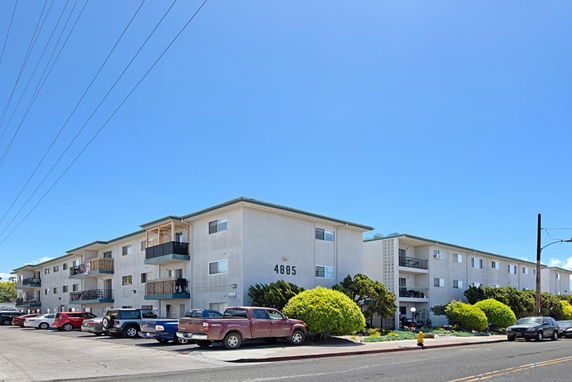 Front view of a multi-story apartment building with parking area.