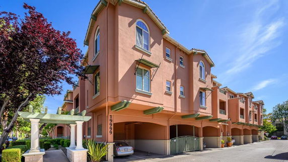 Front view of a multi-story residential building with archways and balconies.