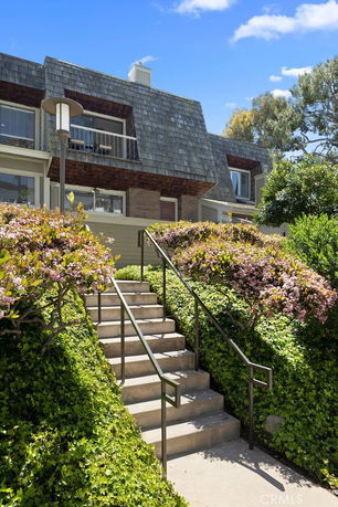 Front view of a multi-story house with a staircase leading to the entrance and dormer windows.