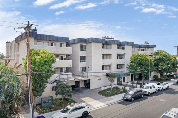 Front view of a multi-story apartment building with balconies and a driveway.
