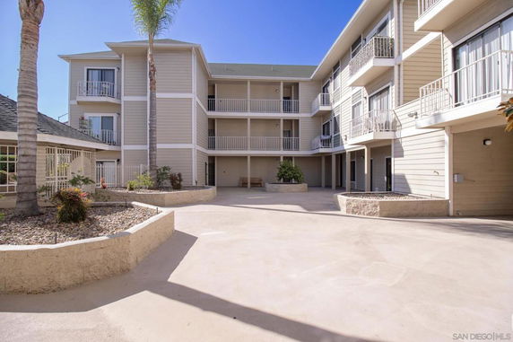 Front view of a multi-story building with balconies and an open courtyard.