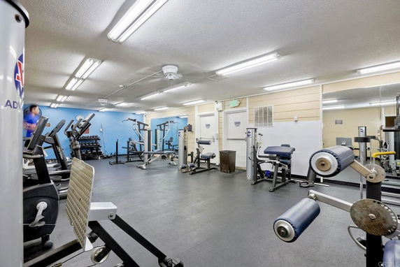 Indoor gym area with various exercise equipment and mirrored walls.